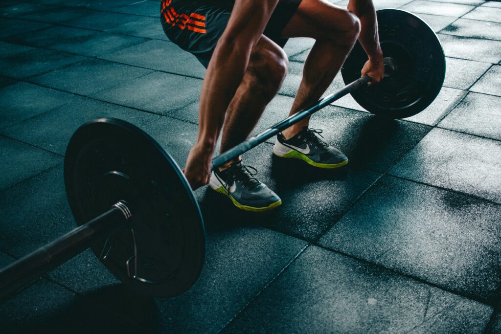 Hombre realizando ejercicio de peso muerto en gimnasio, demostrando fuerza y técnica.